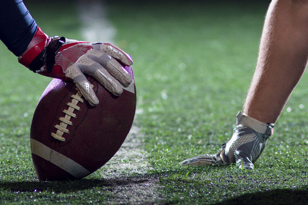 football player hands with football and turf